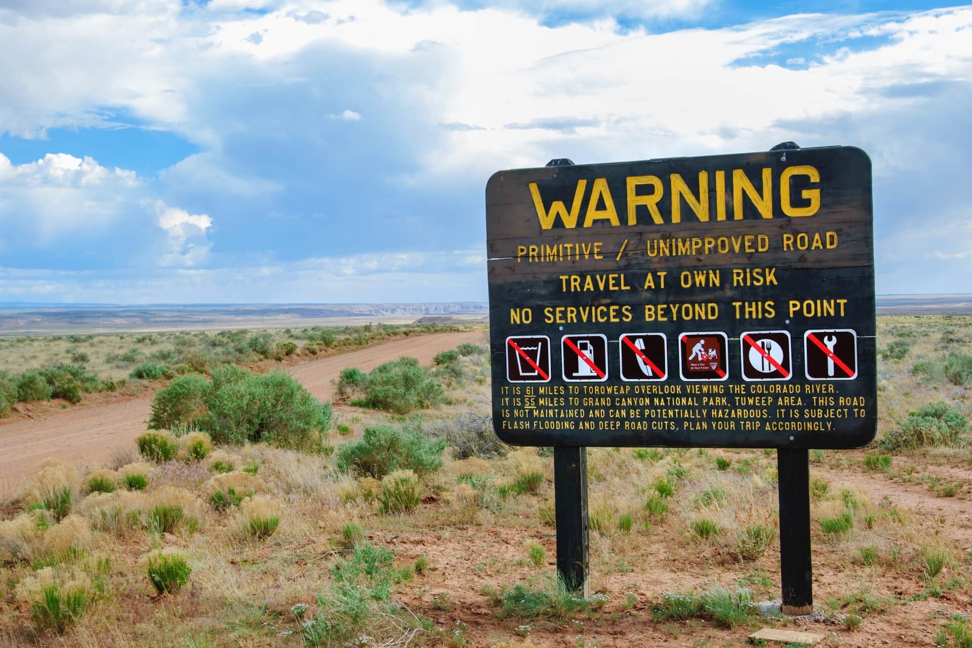 Warning sign next to unpaved road.