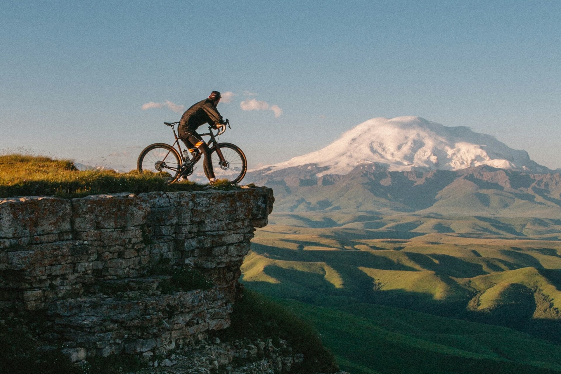 Biker overlooking a mountain at a cliff edge