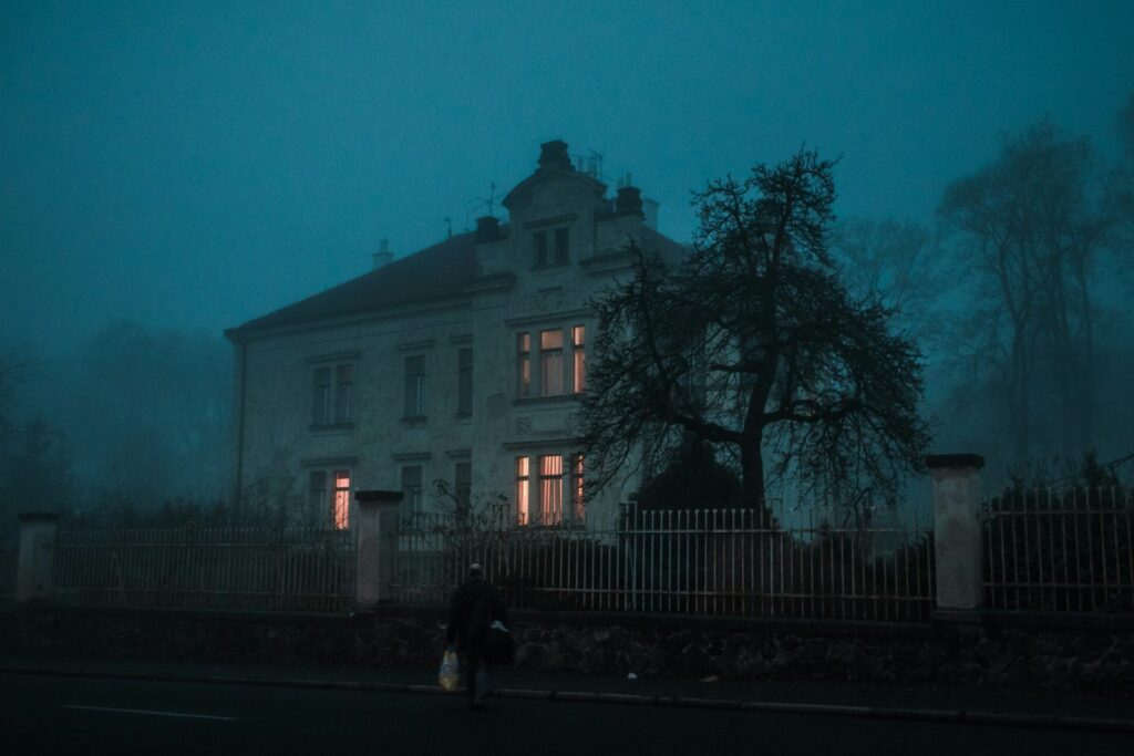 Older mansion with lights on during late dust. 