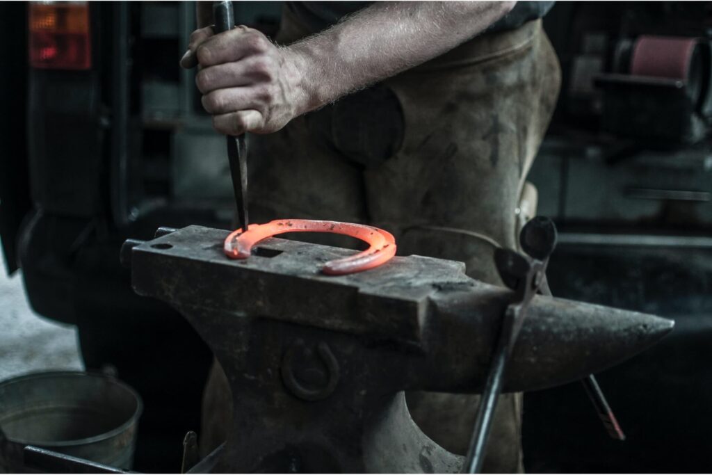 A farrier creating a horseshoe.