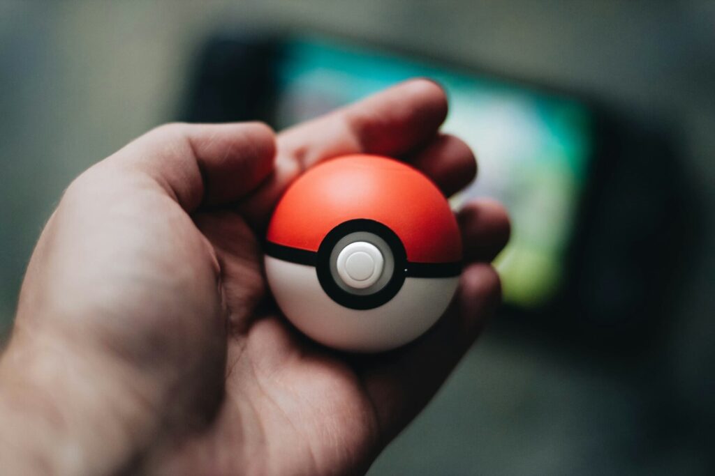 Hand holding red and white Pokeball toy