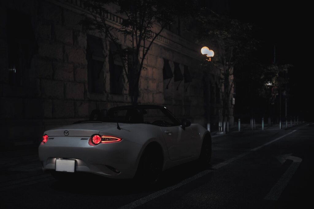 white Mazda Miata on a dim street