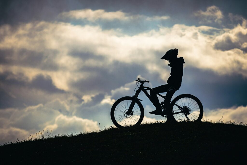 A silhouetted mountain biker alone on a hilltop.