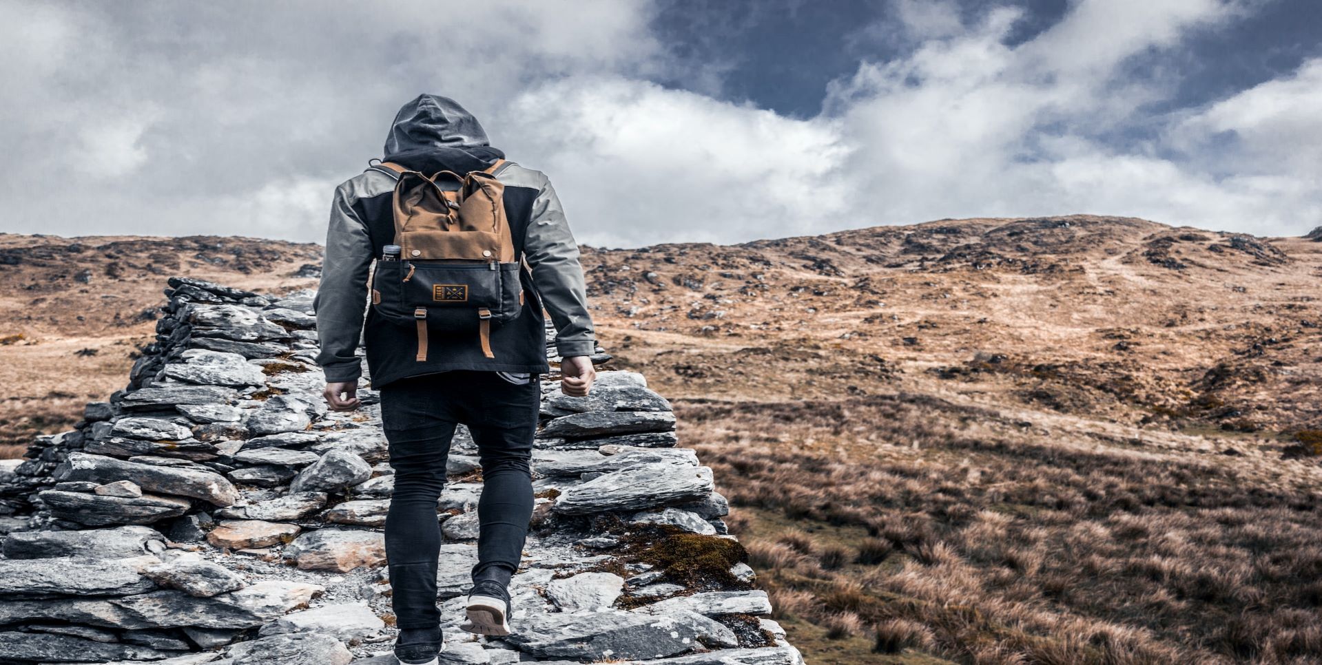 Man with backpack climbing a hill.