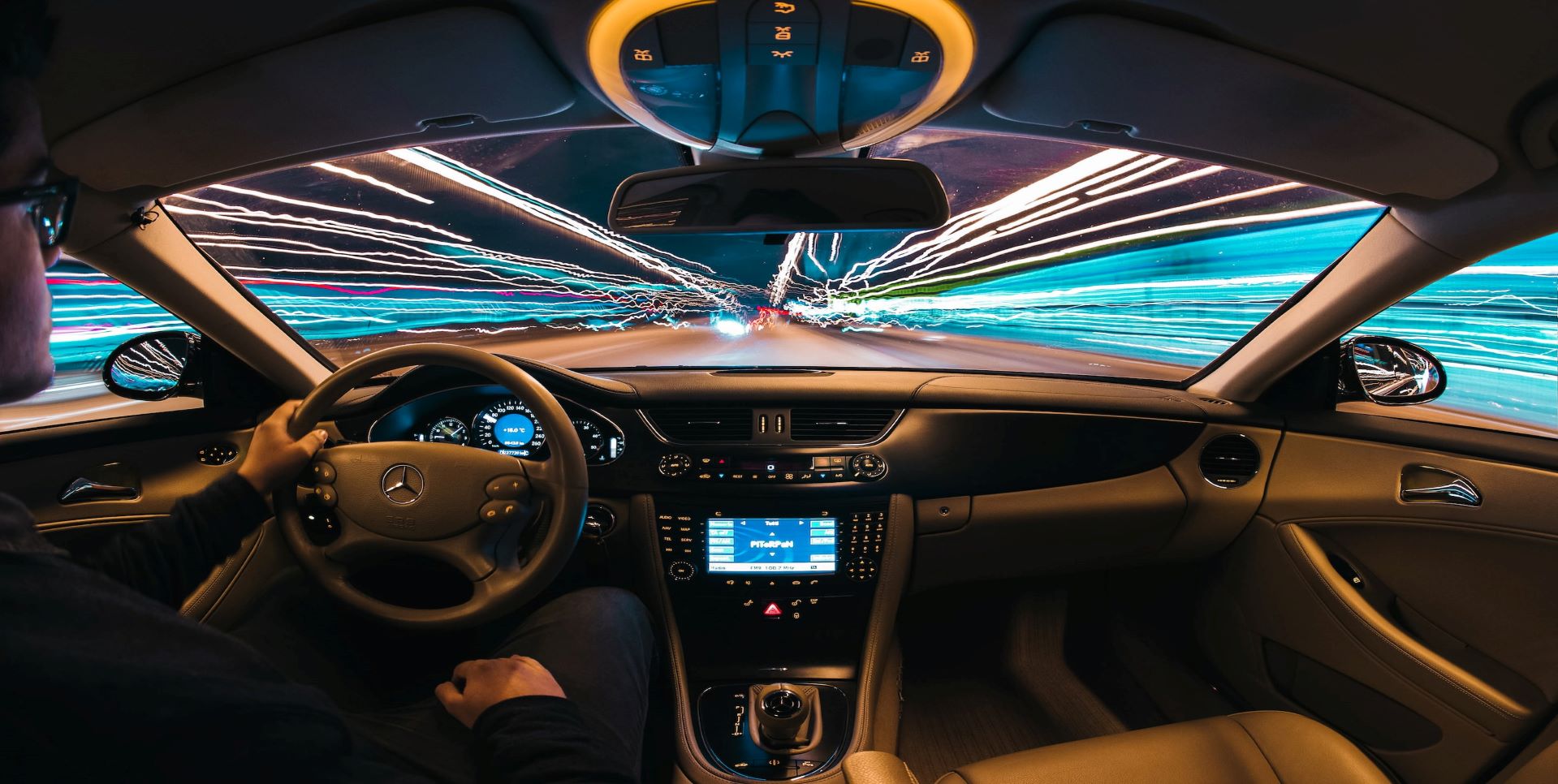 Interior of car driving down the road with streaking lights.