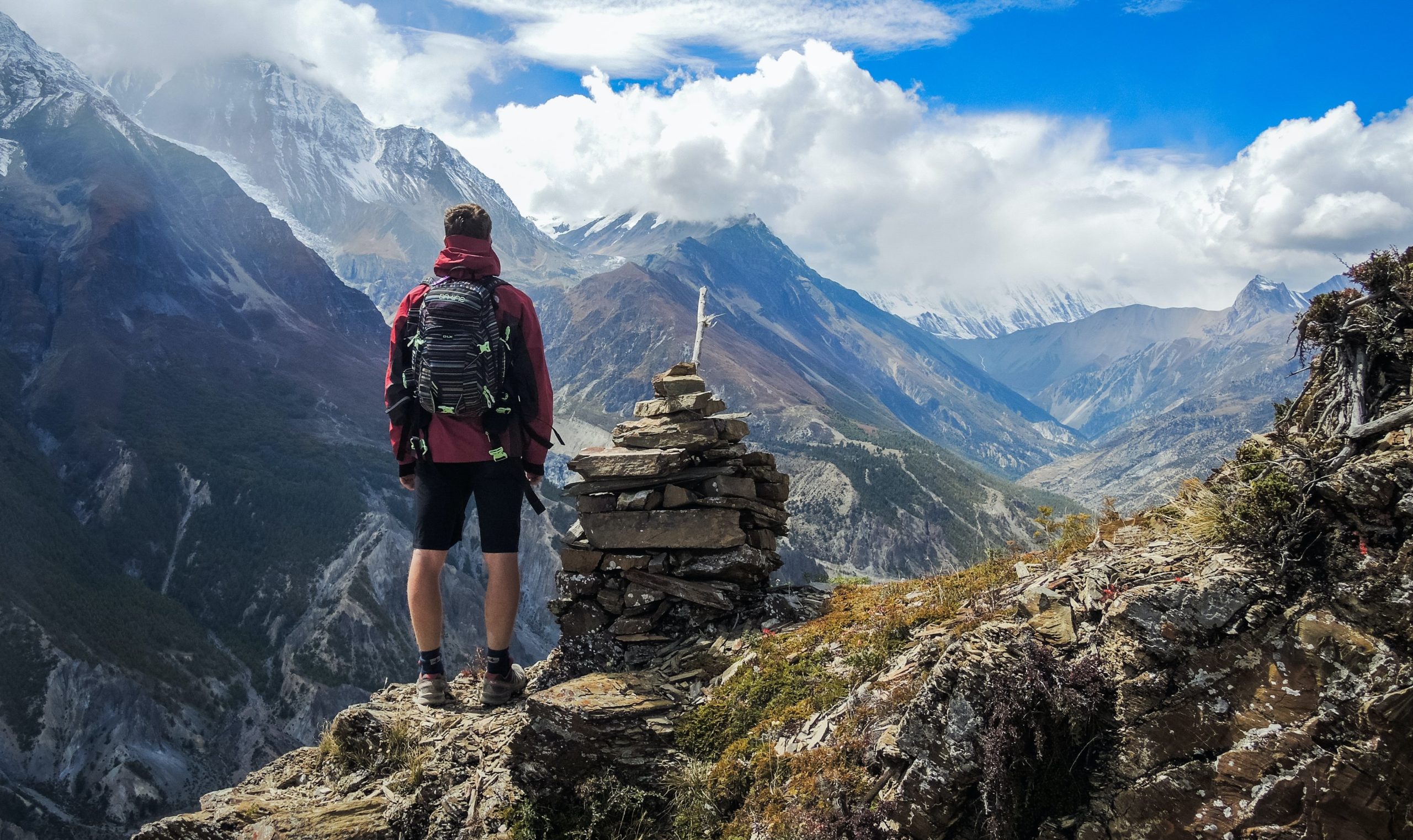 A backpacking man standing on a mountaintop.