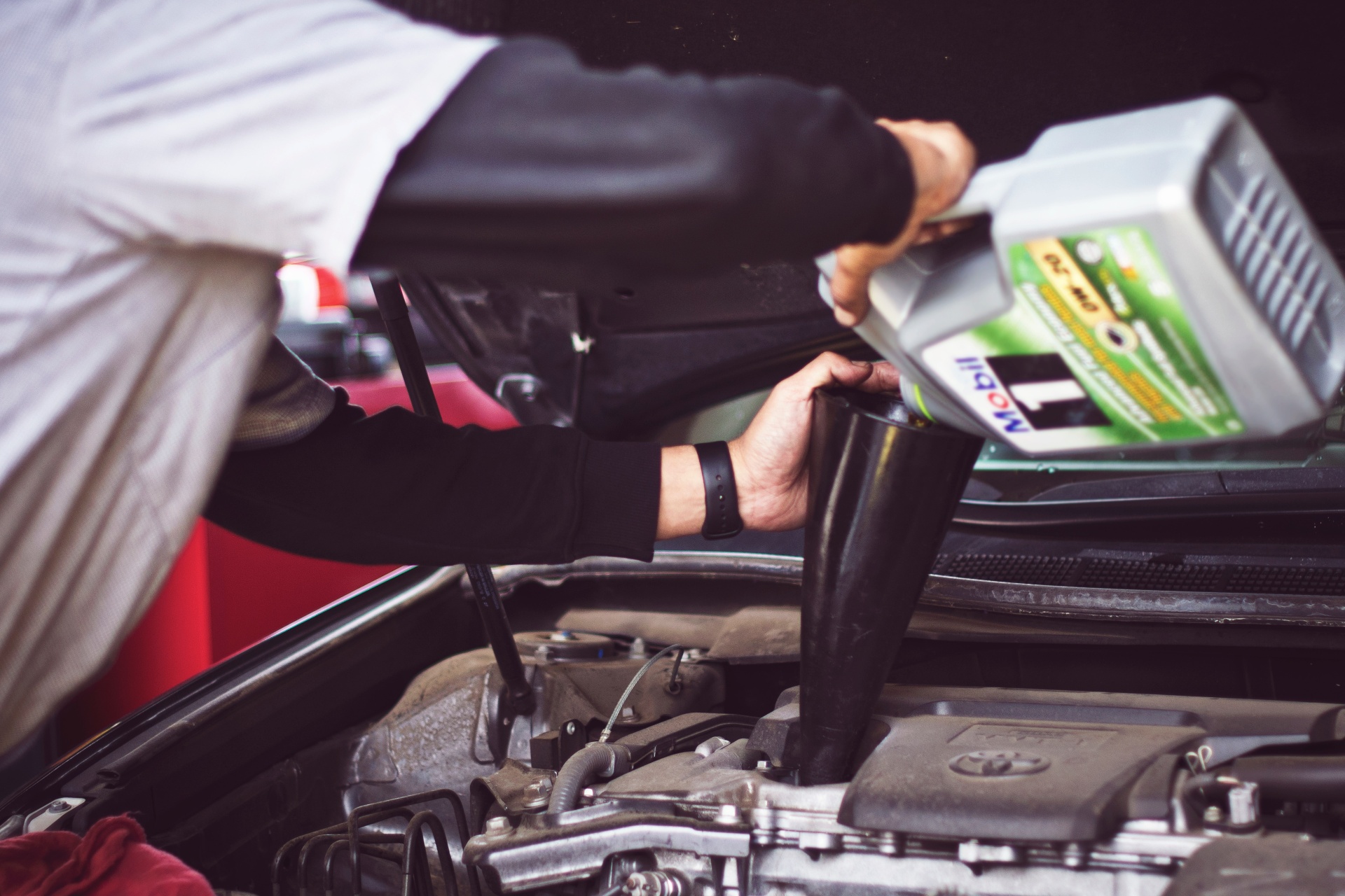 A man pouring motor oil into an engine.