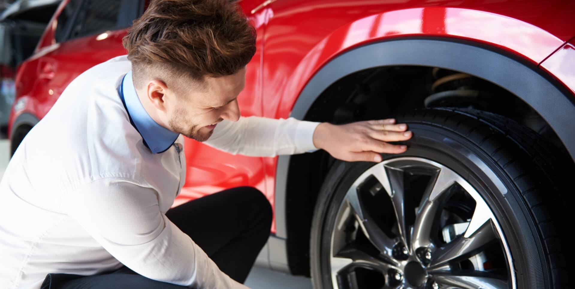 Man crouching by tire.