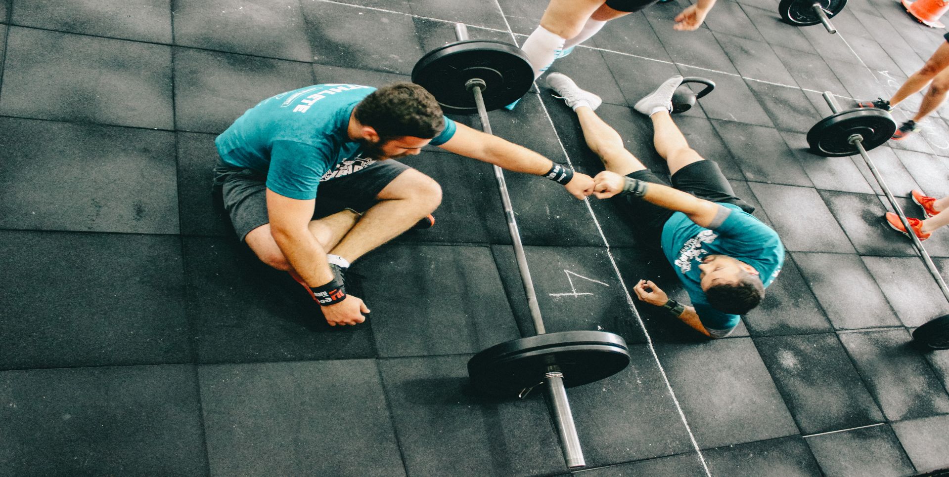 Men who are weight training on the floor of a gym.